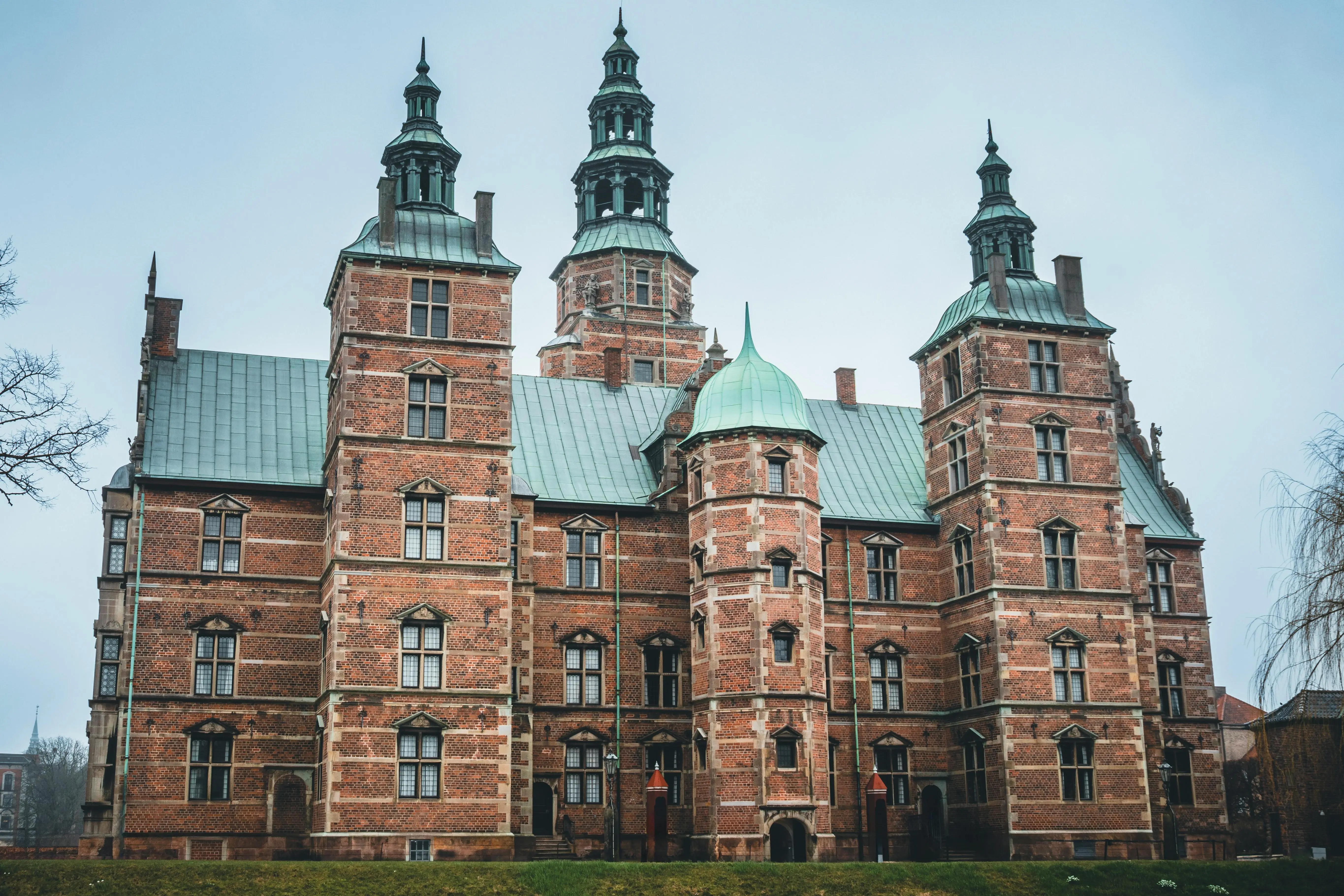 Rosenborg Castle Copenhagen red brick Renaissance architecture surrounded by green King's Garden at golden hour with copper spires gleaming
