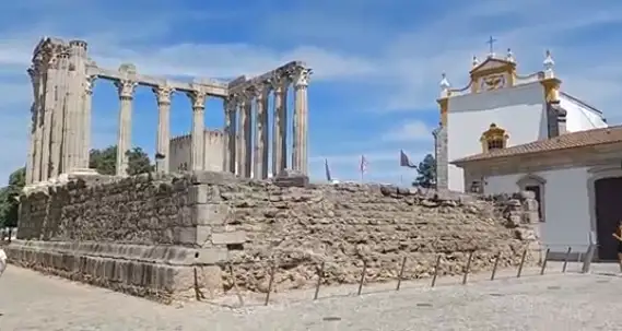 Illuminated Corinthian columns of Évora Roman Temple glowing warmly under twilight sky in historic city center