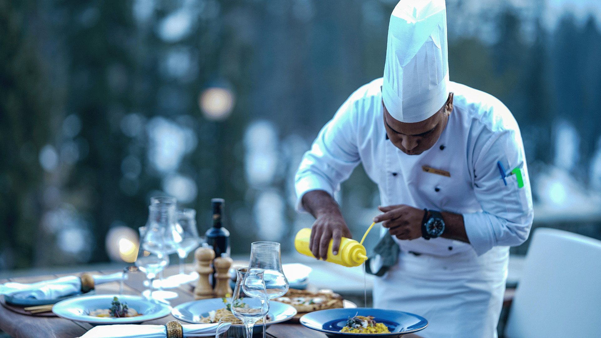 A private chef plating a course at an outdoor dining table