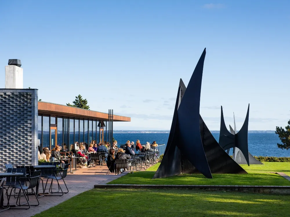 Louisiana Museum modern architecture with sculpture garden overlooking Øresund waters during golden afternoon light in Humlebæk Denmark