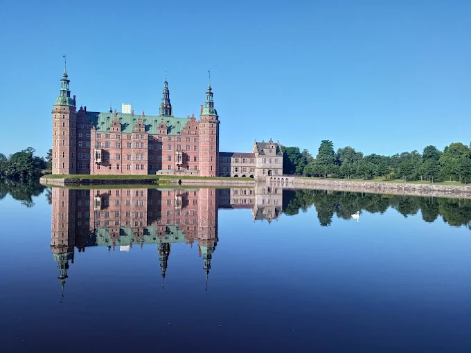 Frederiksborg Castle Dutch Renaissance architecture reflected in Castle Lake waters at golden hour with Baroque garden in Hillerød Denmark