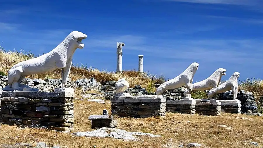 Delos sacred island archaeological ruins with ancient marble columns and Terrace of Lions overlooking turquoise Aegean Sea at golden hour