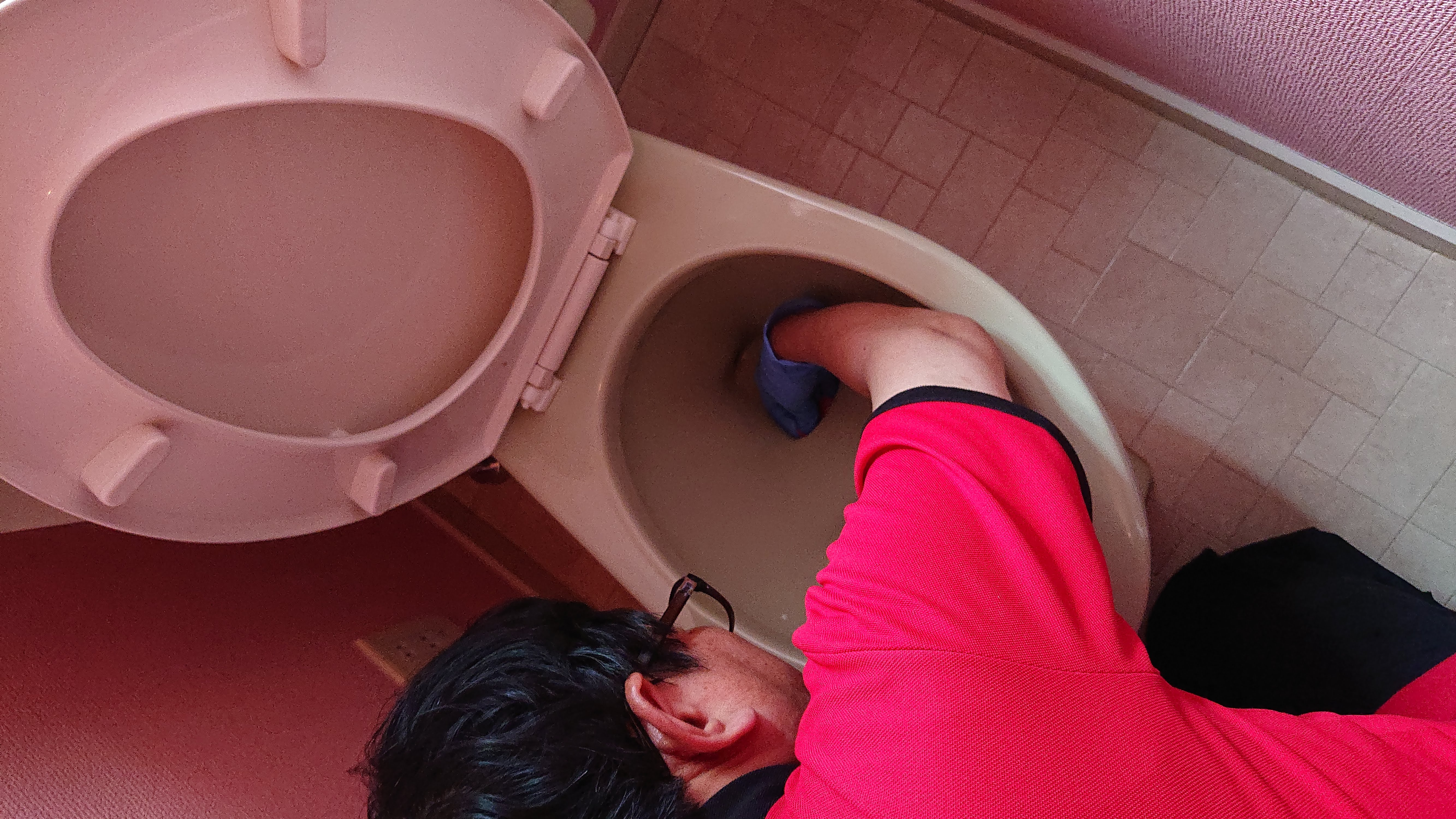 便器縁裏の尿石除去作業中の写真