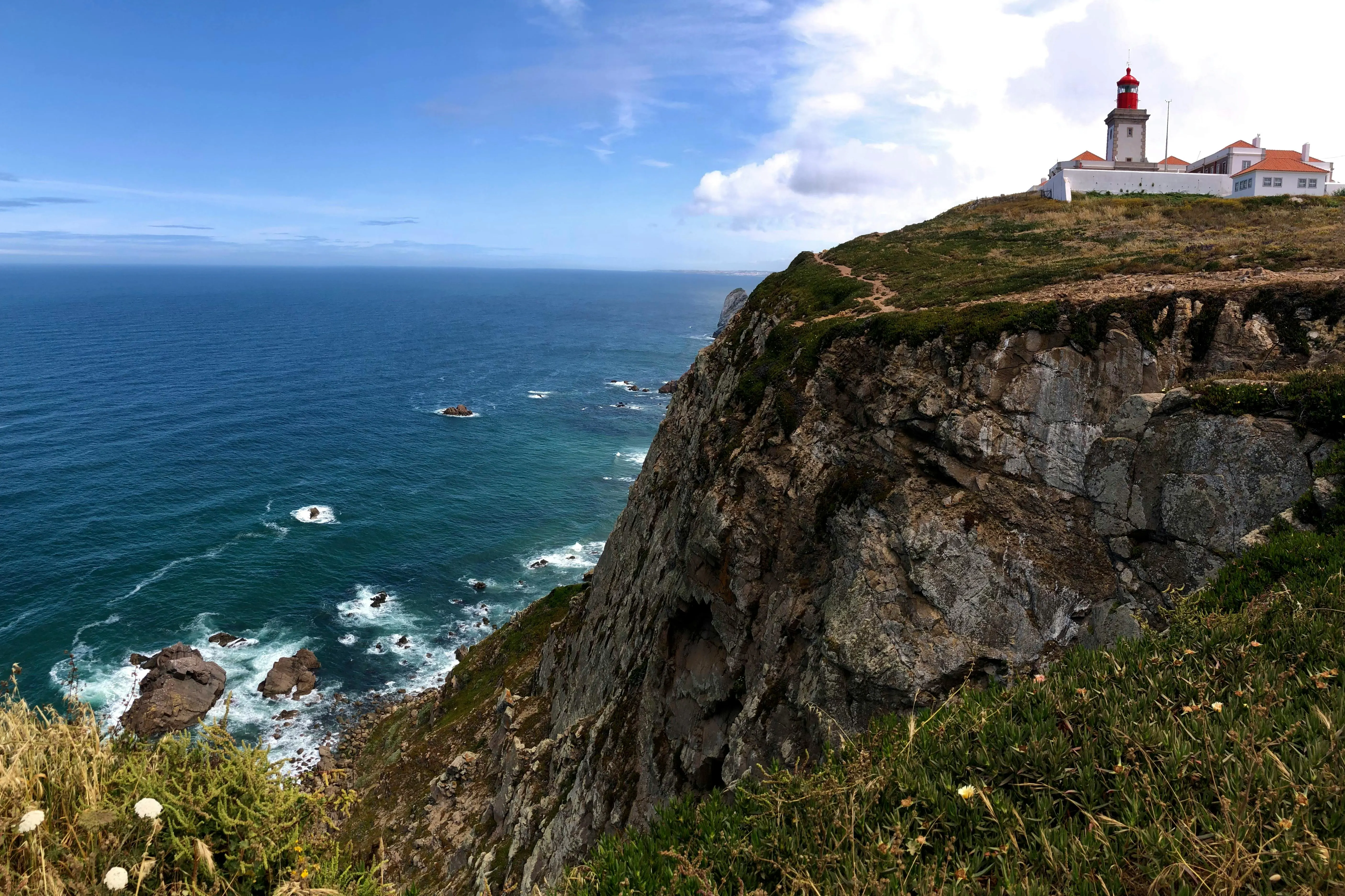 Dramatic crashing waves against the rugged cliffs of Cabo da Roca westernmost point at sunset.