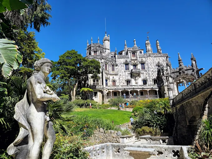 Morning mist swirling around the moss-covered stone spiral staircase of Quinta da Regaleira's Initiation Well.