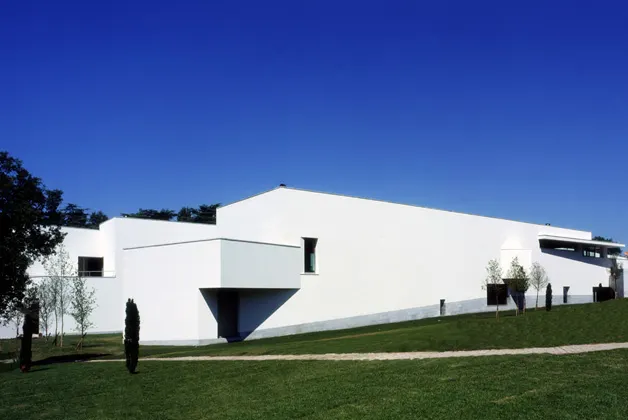 Early afternoon light reflecting off the minimalist Serralves Museum facade surrounded by lush gardens in Porto.