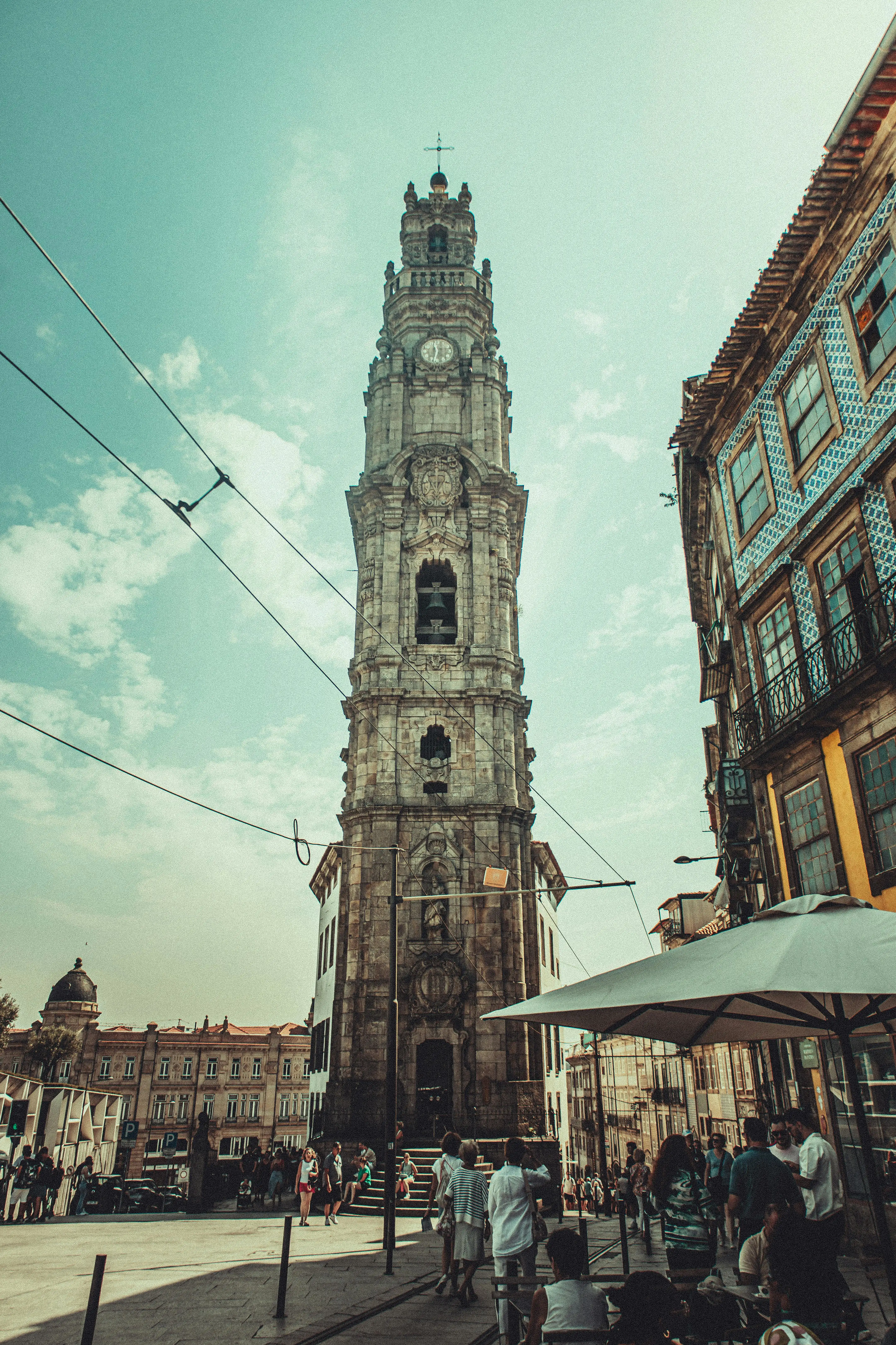 Golden hour sunlight illuminating the ornate Baroque granite Clérigos Tower rising above Porto's red rooftops.