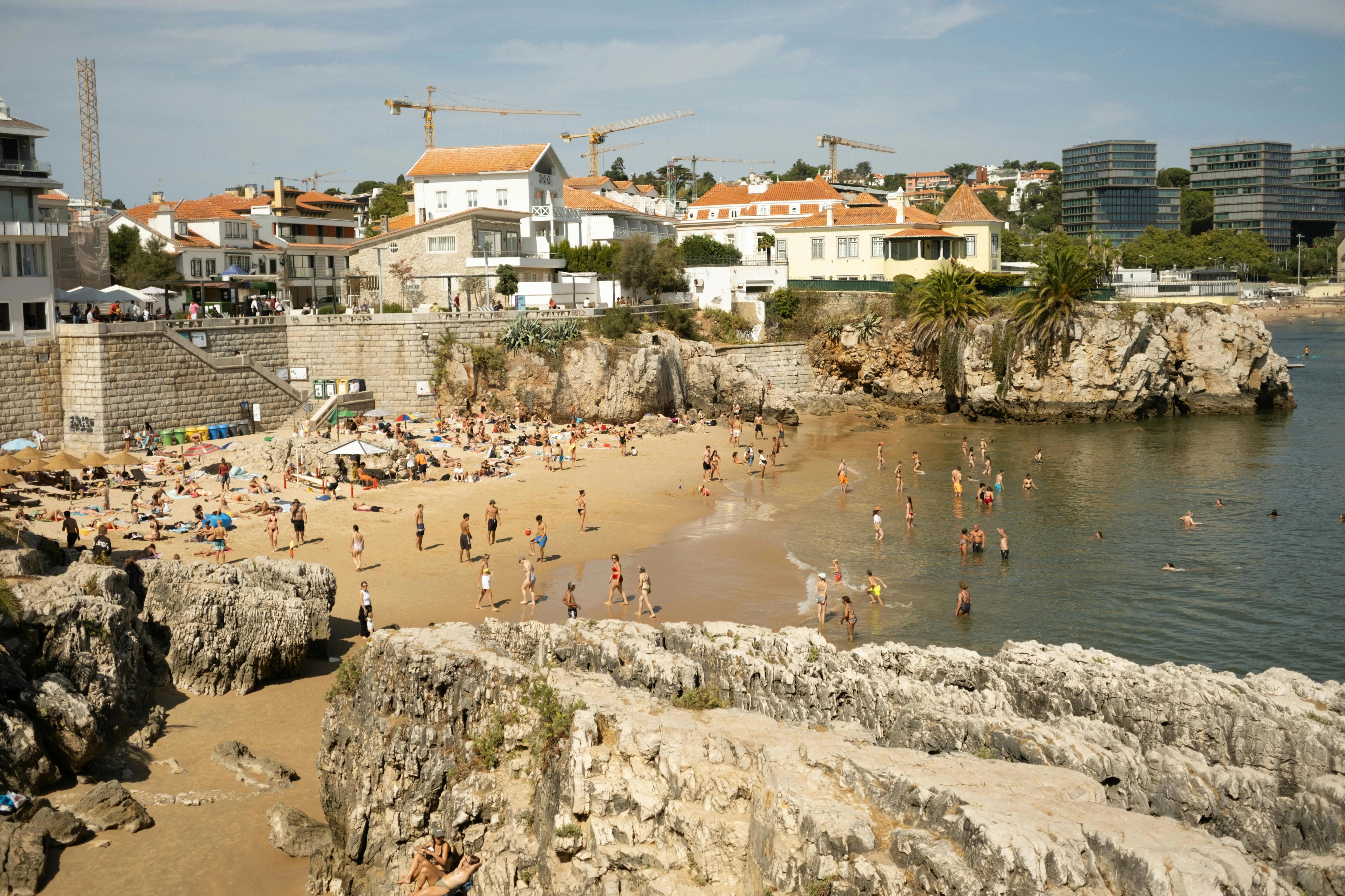 Golden hour sunlight reflecting off the calm waters of Praia da Rainha in Cascais, Portugal.