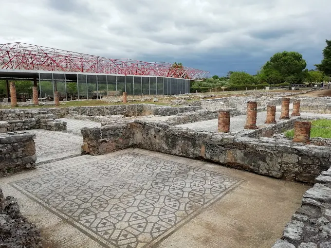 Intricate polychrome Roman mosaic floors of Conimbriga ruins glowing under warm afternoon sunlight with ancient columns