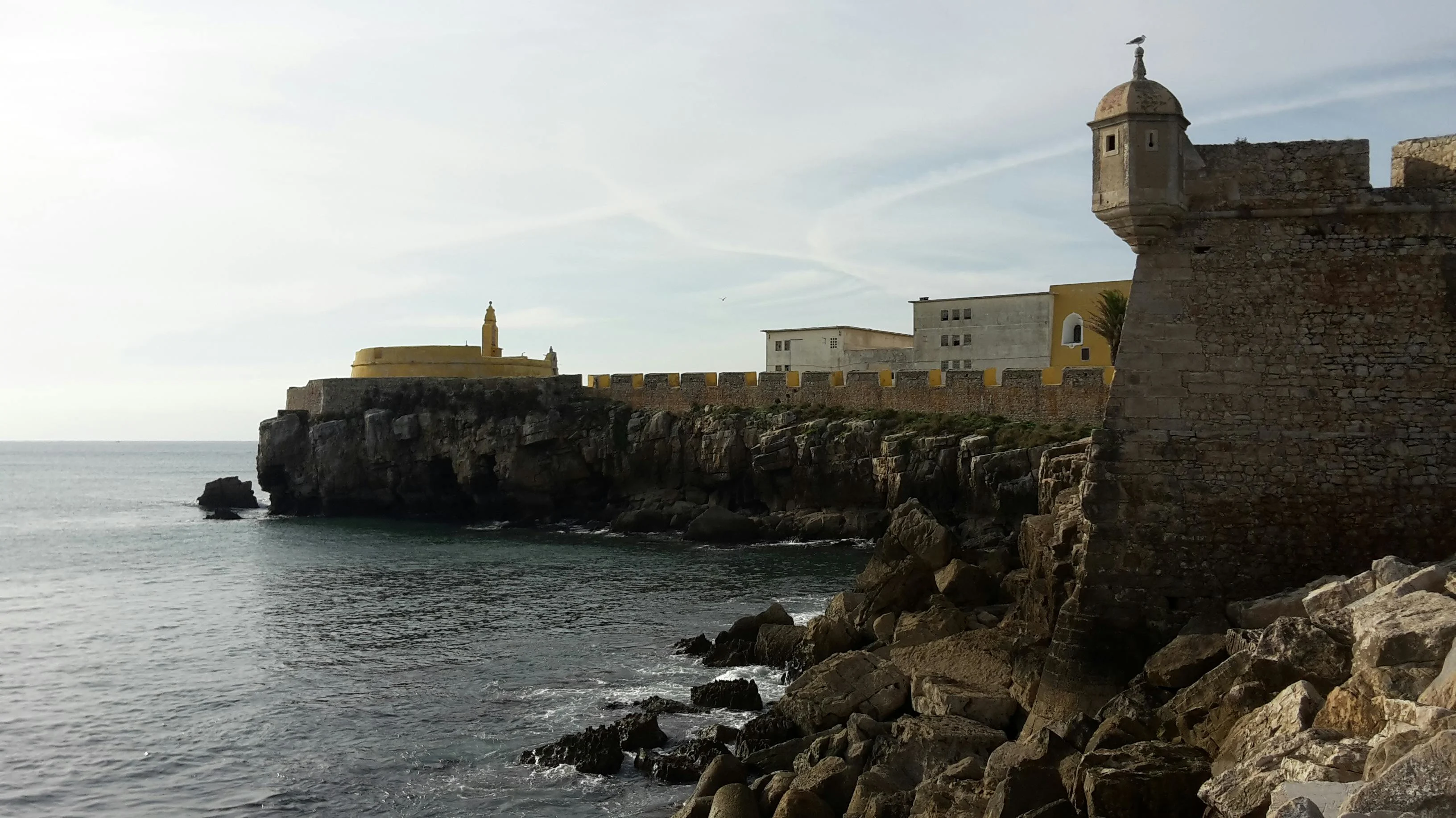 Imposing star-shaped stone walls of Peniche fortress battered by turbulent Atlantic waves under a clear sky