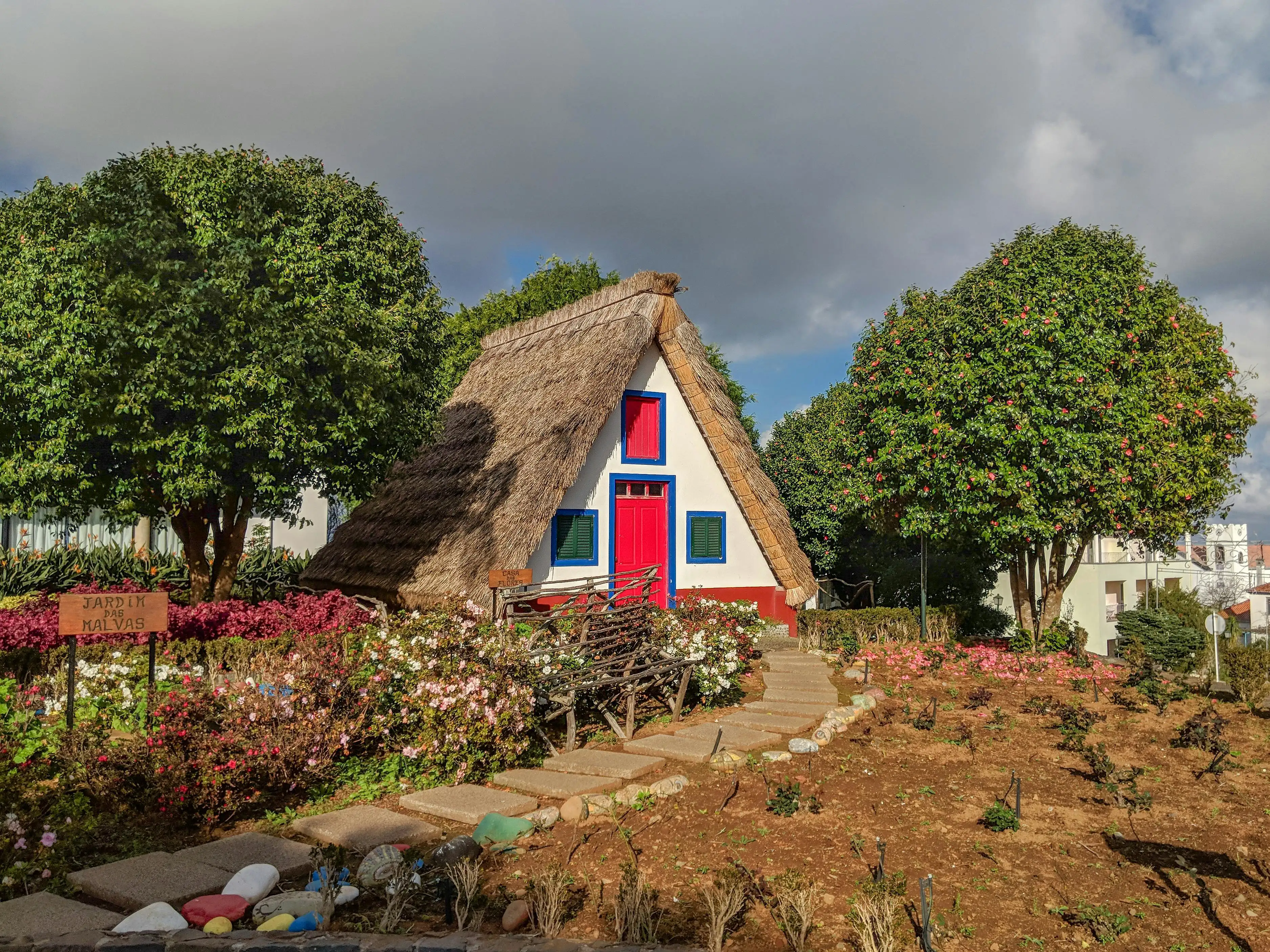 Colorful triangular thatched-roof houses in Santana village, Madeira, surrounded by green hills at golden morning light
