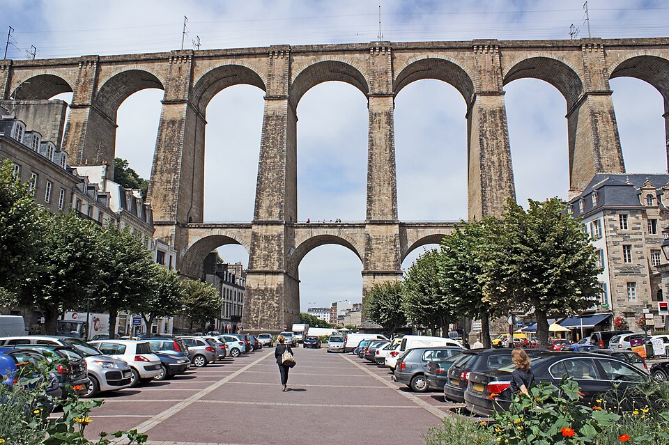 Morlaix viaduct with dramatic stone arches spanning river valley under golden Breton morning light in Brittany, France