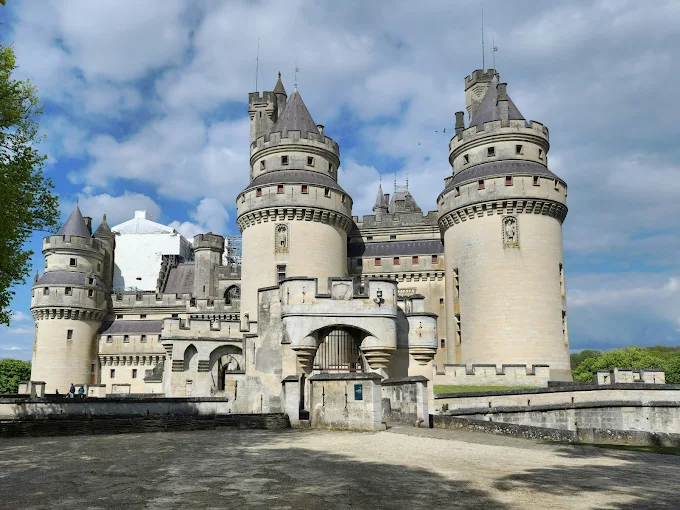 Pierrefonds Castle at sunrise in France, its fairy-tale turrets and fortified walls emerging from the mist with the Compiègne Forest in the background