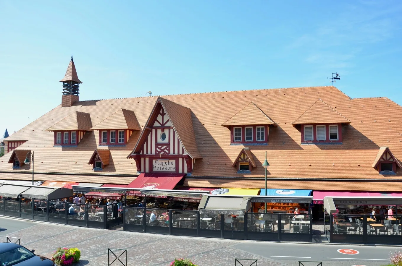Morning light at the Trouville fish market in Normandy, France, with vibrant displays of fresh seafood on ice, colorful fishing boats in the background, and bustling vendors