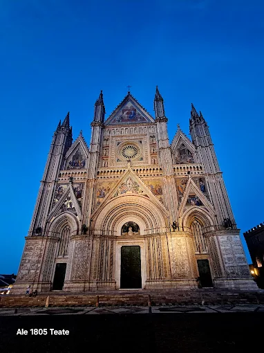 Orvieto Cathedral at golden hour, intricate Gothic façade glowing with mosaic gold against the volcanic tufa cliff backdrop