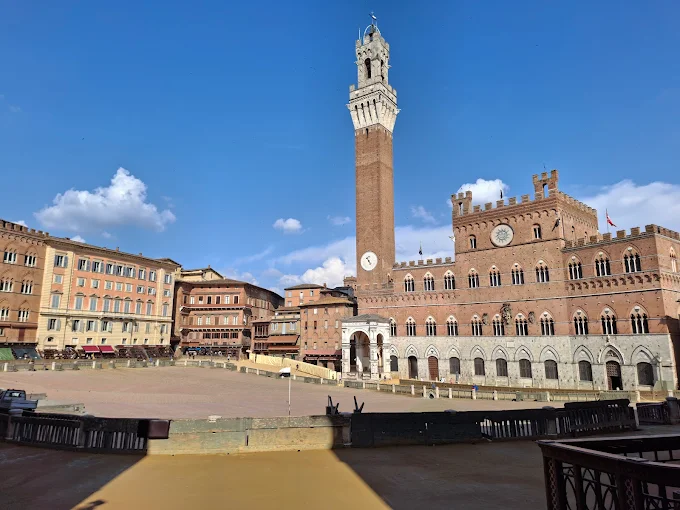 Siena - Piazza del Campo at golden hour, terracotta buildings and brick-paved fan-shaped square glowing under soft evening light