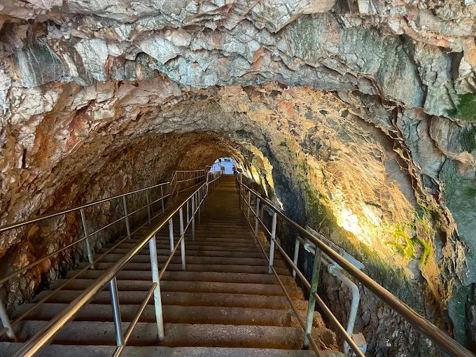 Sunlight streaming into the vast La Grave chamber of Castellana Grotte caves, with dramatic limestone formations and a sense of deep underground silence at midday