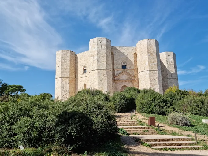 Castel del Monte's perfect octagonal fortress glowing in the golden afternoon light, surrounded by rolling Apulian countryside under a clear blue sky