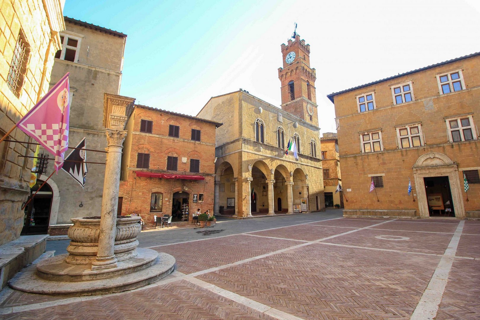 Pienza Renaissance town at golden hour, terracotta rooftops and travertine façades glowing under soft sunset light with Val d’Orcia hills in the distance