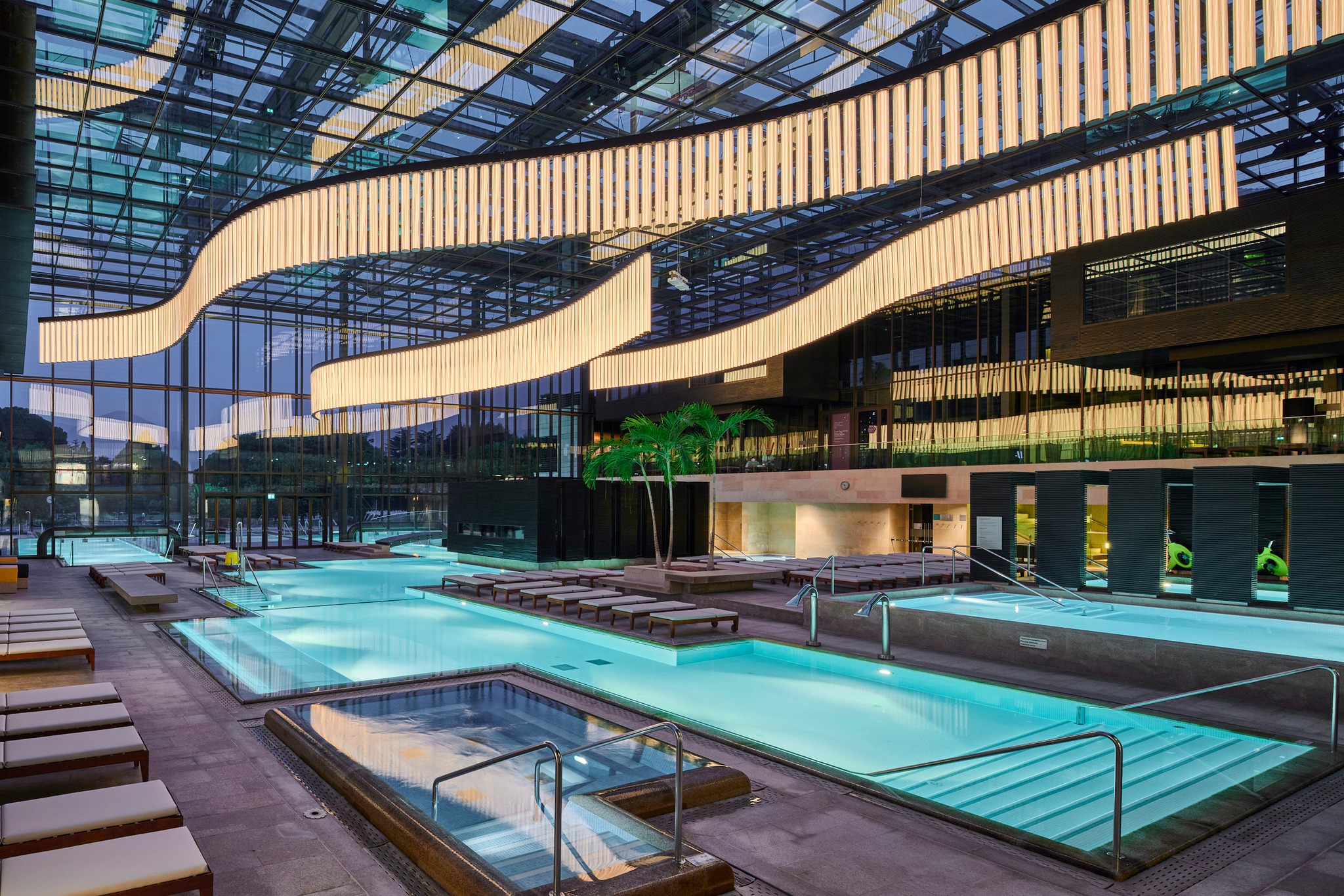 Sunset over Merano Thermal Baths in South Tyrol, Italy, with modern architecture reflecting alpine peaks and steaming thermal pools at golden hour