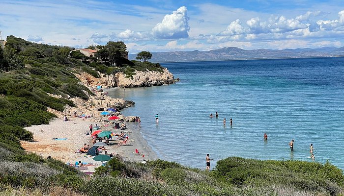 Turquoise waters of Porto Paglia beach in Portoscuso meeting golden sand with dramatic granite outcrops under Sardinian mid-morning sun