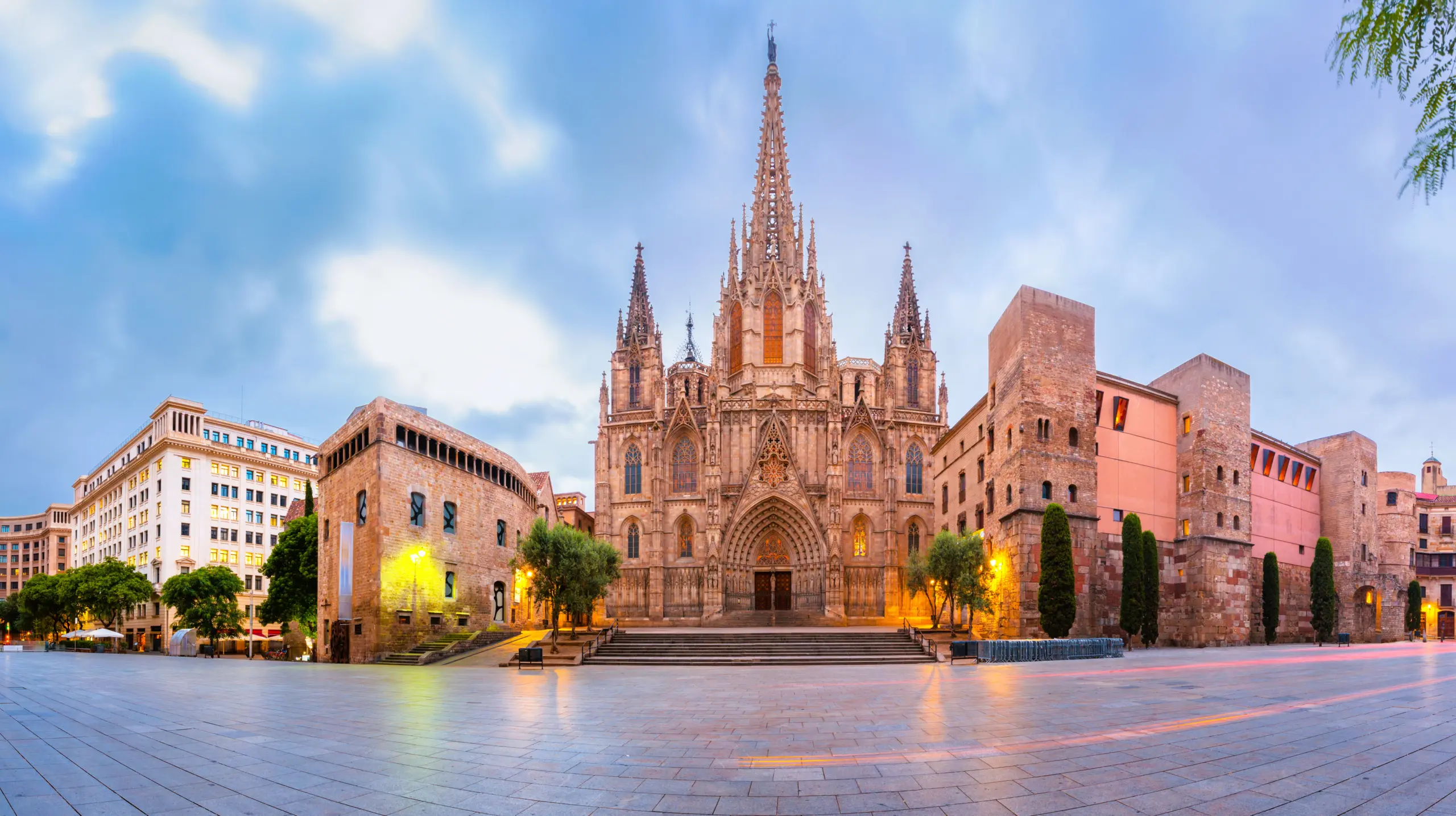 Gothic Quarter Barcelona at twilight with narrow medieval streets illuminated by wrought-iron lanterns and Gothic arches casting dramatic shadows