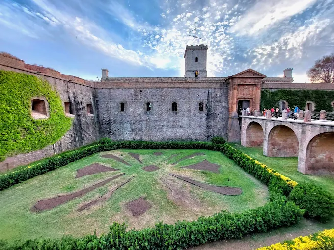 Montjuïc Castle at sunset with golden light illuminating stone ramparts and panoramic views of Barcelona coastline