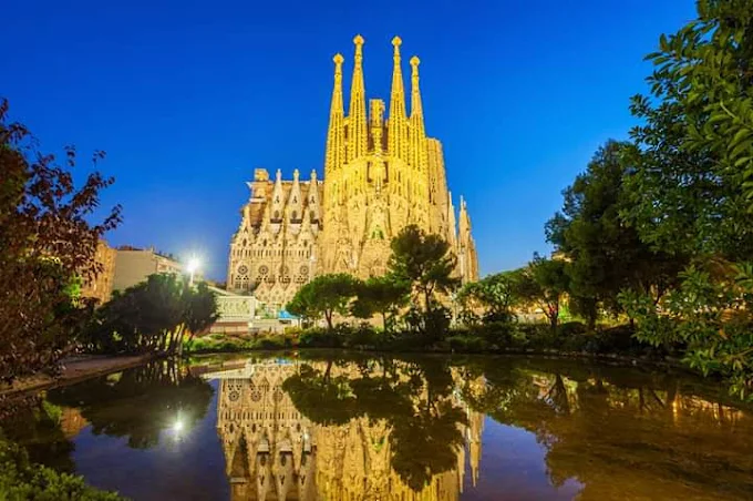 Sagrada Família bathed in morning light with sunlight filtering through stained glass creating kaleidoscopic patterns on stone columns in Barcelona