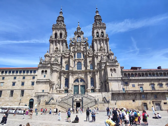 Santiago de Compostela Cathedral facade at sunset with granite towers and pilgrims bathed in warm Galician evening light