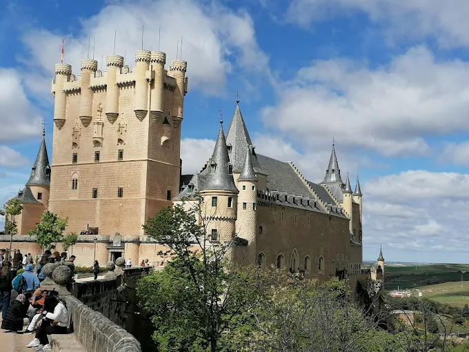 Alcázar of Segovia fairytale castle at sunset with conical towers and stone walls bathed in warm Castilian evening light