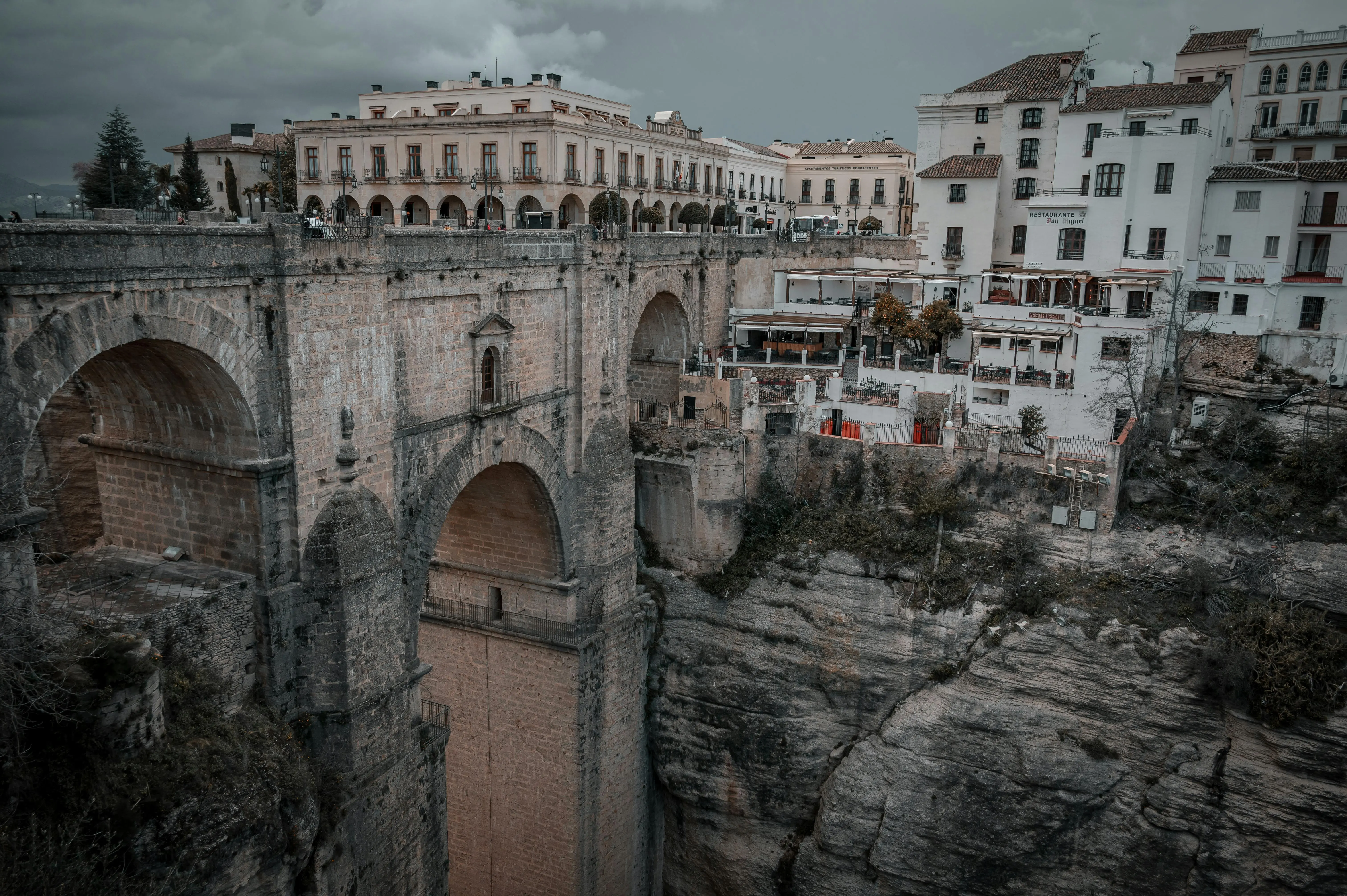 Ronda Puente Nuevo bridge spanning deep El Tajo gorge with white village houses and dramatic cliffs bathed in golden Andalusian sunlight