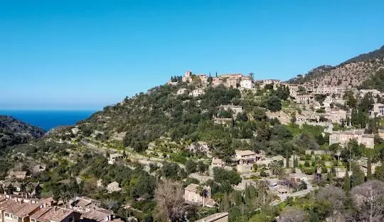 Deià village stone houses with bougainvillea and mountains bathed in warm Mediterranean light