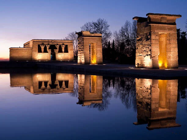 Temple of Debod ancient Egyptian temple at sunset with sandstone columns, reflecting pool, and Madrid skyline bathed in warm golden light
