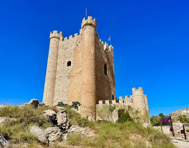 Alcalá del Júcar castle overlooking winding Júcar River at sunset in Castilla-La Mancha, Spain with white cave houses carved into limestone cliffs