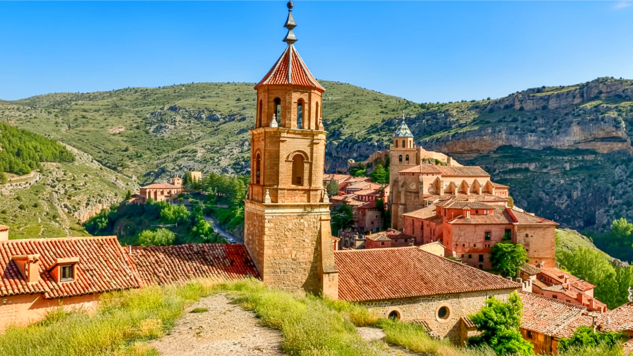 Albarracín medieval town pink limestone walls glowing at sunset in Teruel province, Aragon, Spain with mountain backdrop