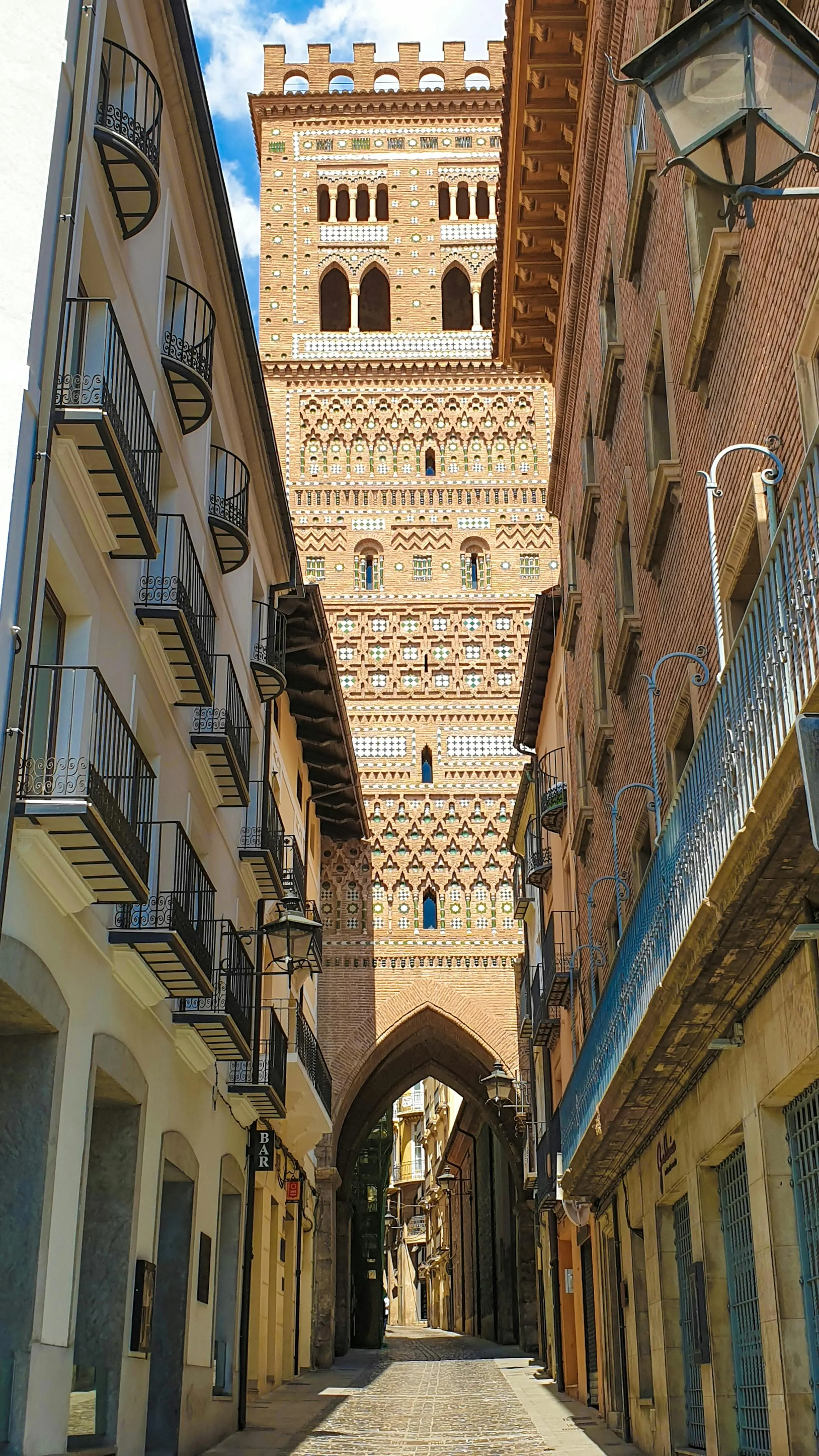 Teruel Mudéjar towers glowing in golden sunset light against blue sky in Aragon, Spain with intricate brickwork details visible