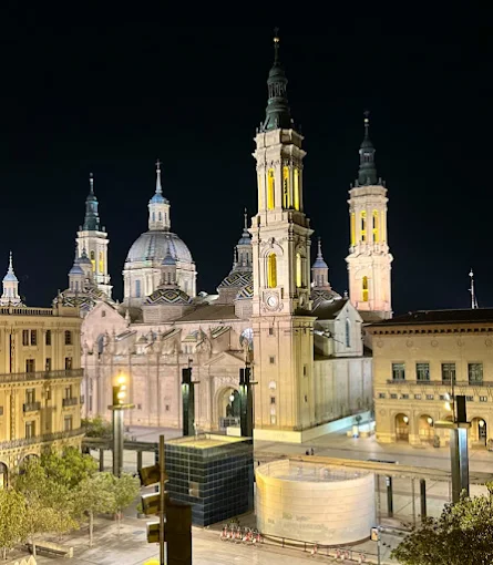 Zaragoza Basílica del Pilar domes reflecting on Ebro River at sunset in Aragon, Spain with warm golden light illuminating baroque architecture