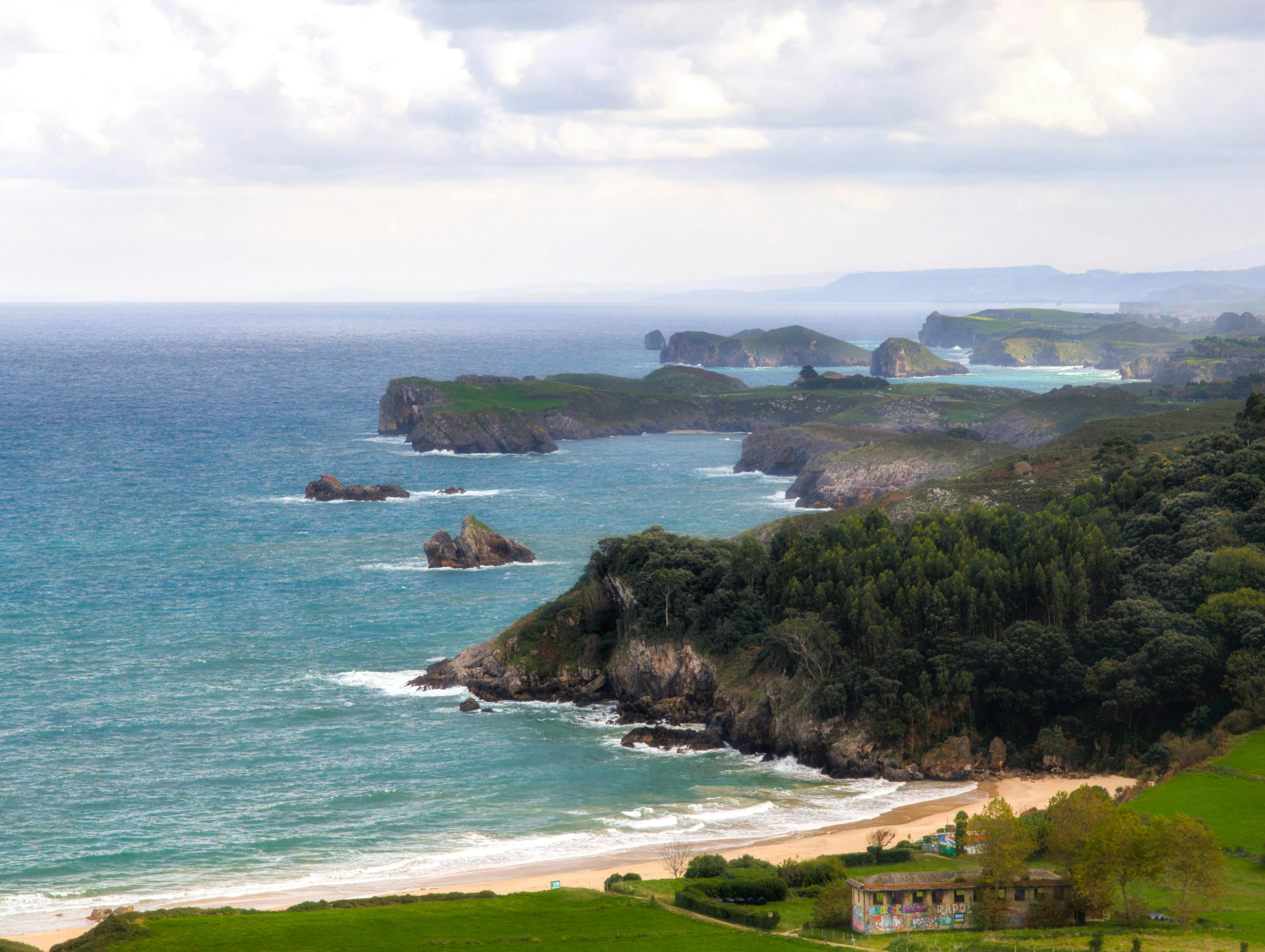Asturias green coast cliffs meeting Atlantic Ocean waves at sunset in northern Spain with lush vegetation and dramatic sky