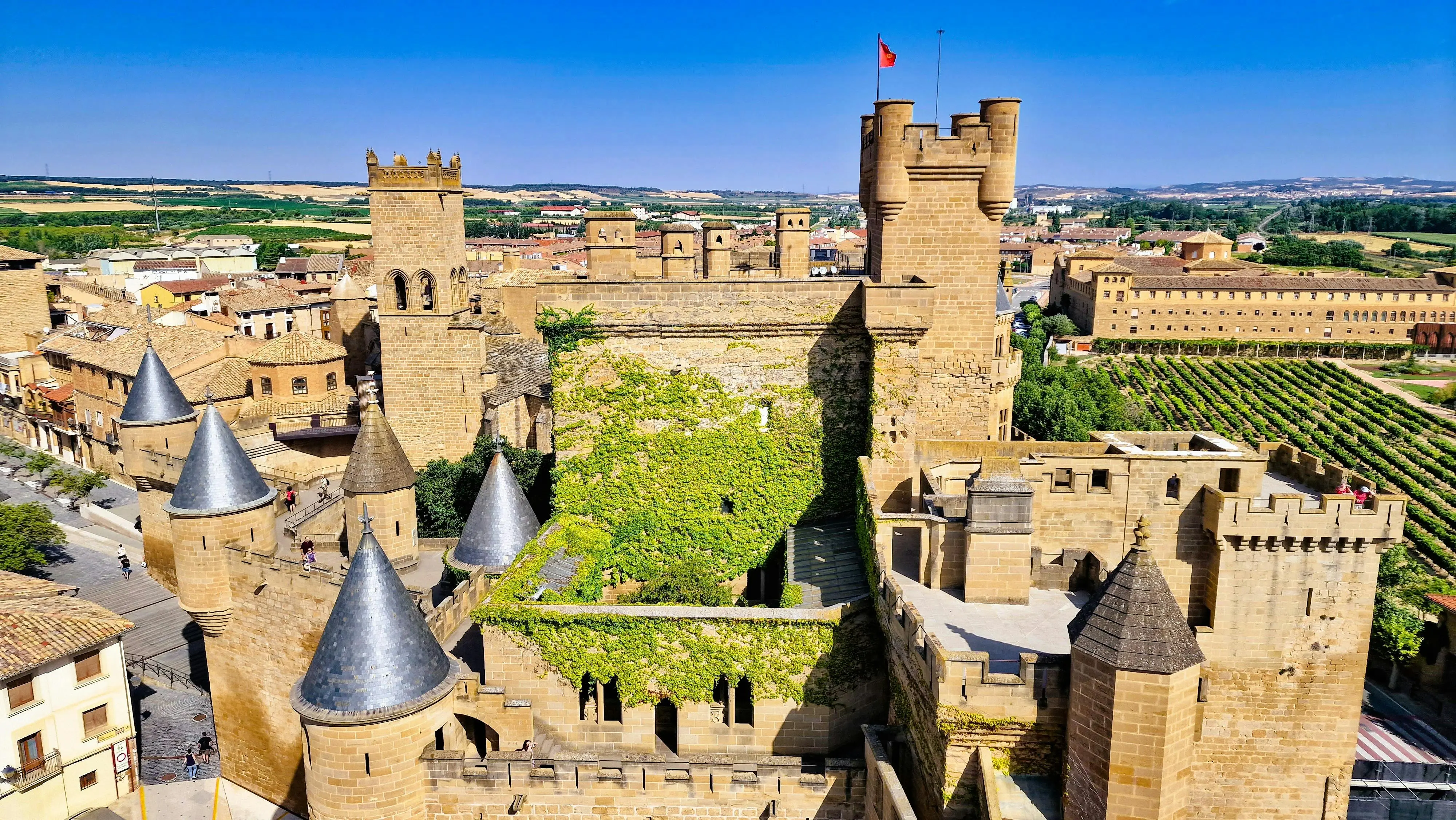Olite Castle towers rising at golden hour with Gothic turrets and crenellated walls against Navarre vineyards, medieval palace of Kings of Navarre, Spain