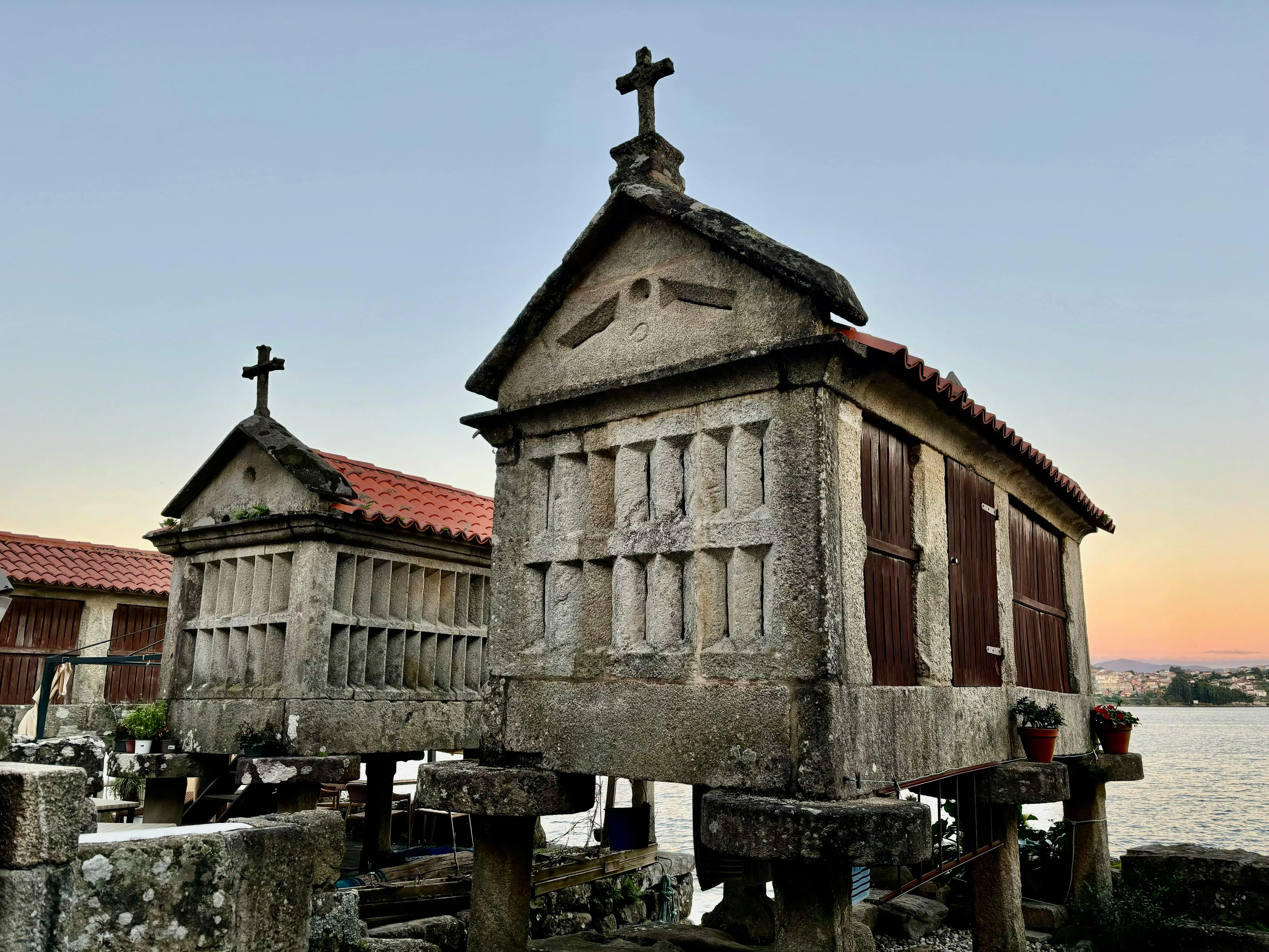 Combarro hórreos stone granaries standing in tidal water at sunset in Ría de Pontevedra, Galicia, Spain with fishing boats