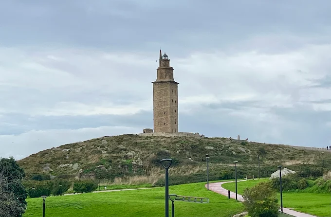 Tower of Hercules ancient Roman lighthouse standing on granite cliffs overlooking Atlantic Ocean at sunset in A Coruña, Spain with dramatic sky