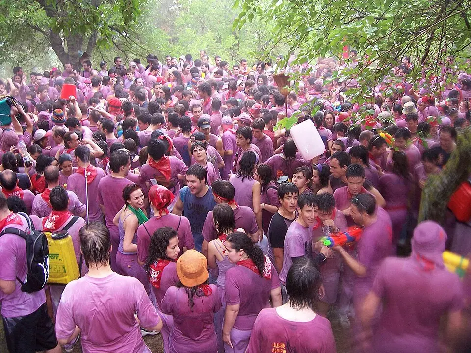 Haro Wine Battles participants spraying red wine from bottles on white shirts at Bilibio Cliffs in La Rioja, Spain during June festival