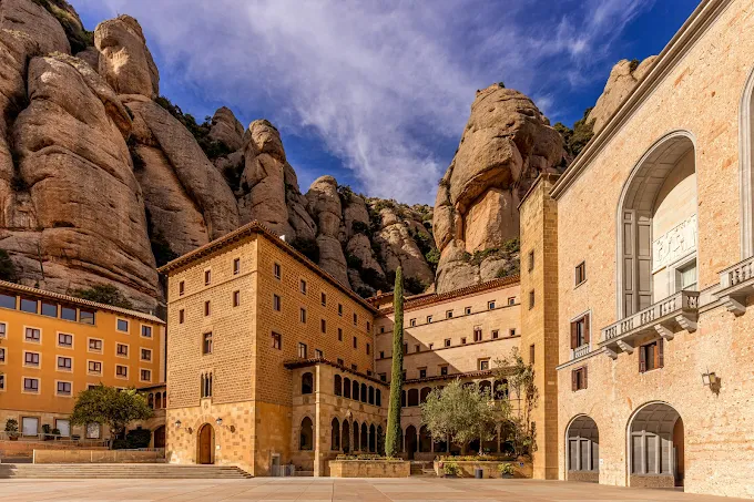 Montserrat monastery basilica at sunrise with jagged rock formations and mist, Catalonia spiritual sanctuary, Spain