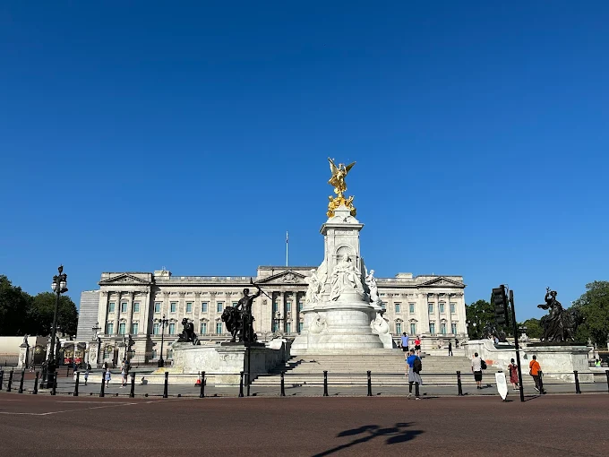 Buckingham Palace facade at golden hour with Victoria Memorial gold statue gleaming in foreground London