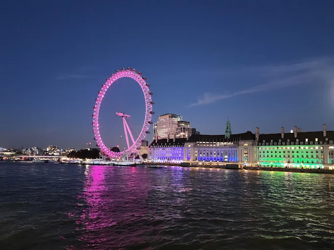London Eye Ferris wheel at twilight with Thames River reflecting purple sky and Westminster Bridge lights London