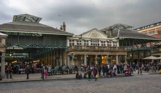 Covent Garden Piazza at golden hour with street performers and historic glass roof market structure London