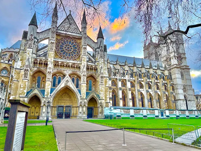 Westminster Abbey Gothic facade at dusk with warm interior light glowing through stained glass windows London