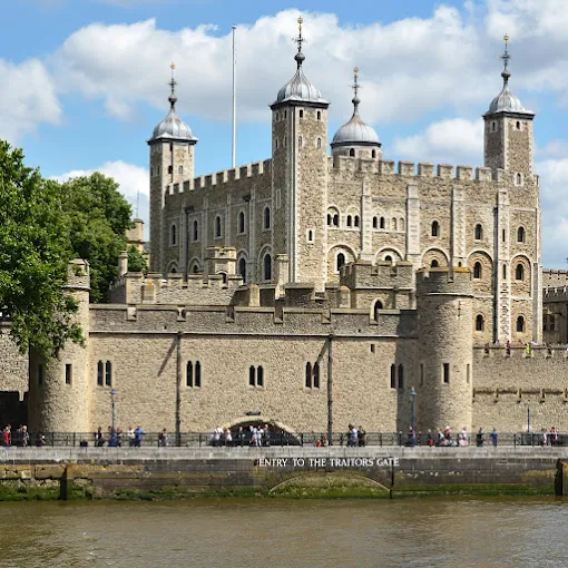 Tower of London White Tower at sunrise with Thames River mist and ravens perched on ancient stone walls