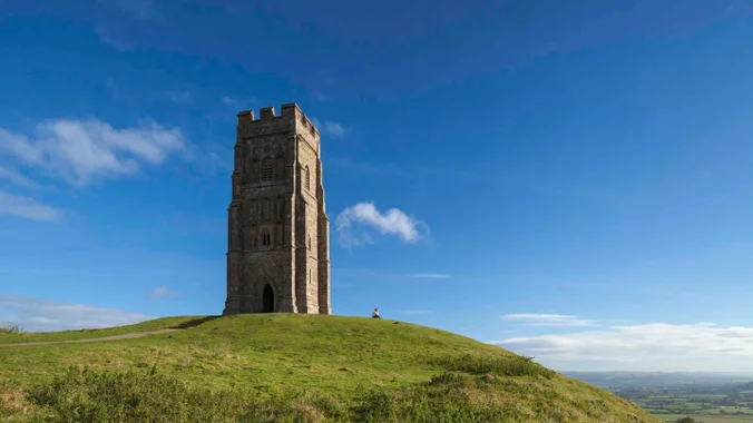Glastonbury Tor tower silhouetted against sunrise mist over Somerset Levels in England