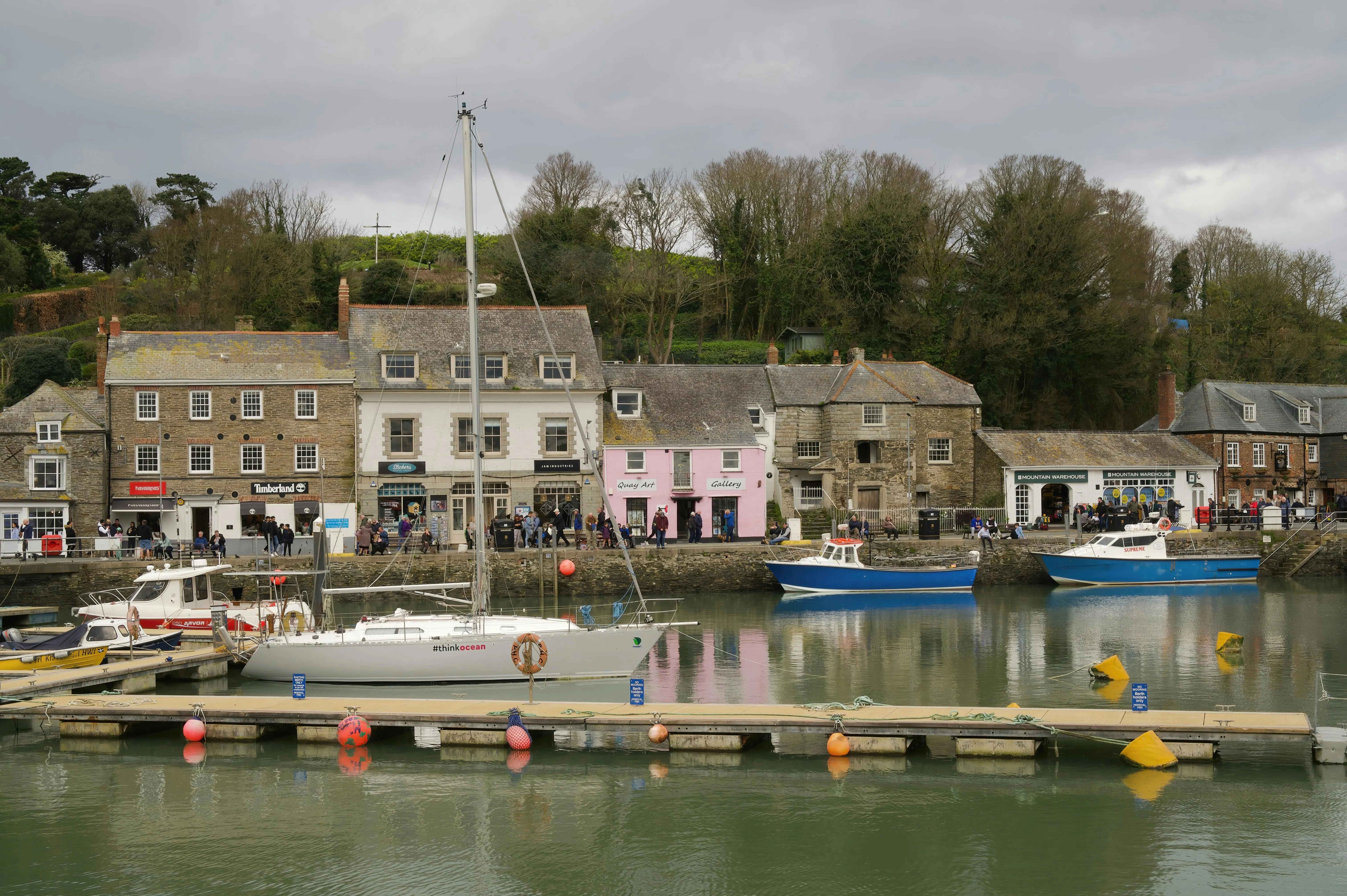 Padstow harbor fishing boats moored at golden hour with historic buildings lining the quay in Cornwall England